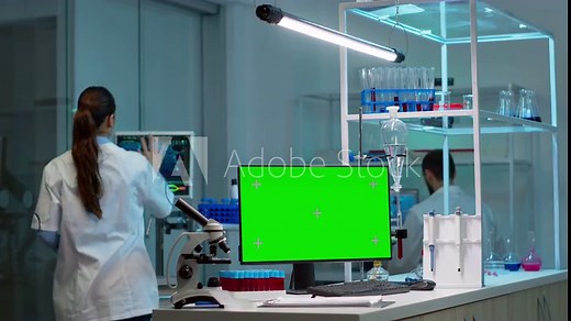 Team of scientists working in background of modern laboratory using computer with green screen, mockup display, chroma key monitor, analysing experiment evolution, high tech development lab.