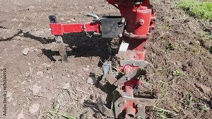 Slow motion view of rotary tiller (also known as rotavator). Cultivation of soil in small farm field. Detail view of agriculture machine.
