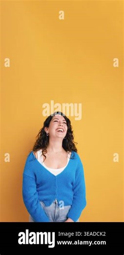 Happy young woman with curly hair laughing out loud. Shes standing in front of a yellow background, expressing genuine joy and happiness. Vertical Stock Video Footage - Alamy