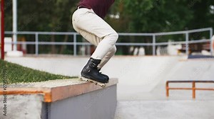 Aggressive Inline roller skater doing tricks in concrete skatepark outdoors with beautiful background, super slow motion