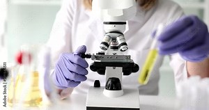 Glass test tubes with yellow oily liquid scientist works on microscope