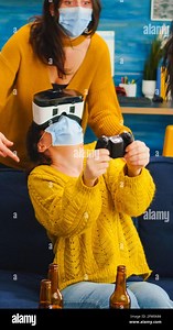 Mixed raced friends in living room having video game competion experiencing virtual reality keeping social distancing wearing masks to prevent sickness with covid. Diverse people in new normal party Stock Photo - Alamy