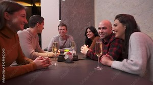Company of friends having fun in the bar. They sit at the table with drinks and waiter brings cocktails. Friends are happy, they are enjoying night out in a nice place.