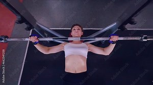 Woman in the gym trains on bodybuilding machines. A woman pumps her muscles on a simulator. Training of the female body on a sports machine.