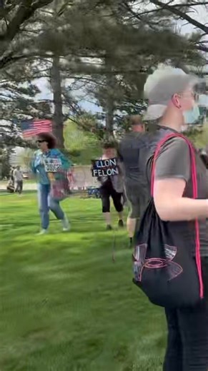 People are lined up with signs protesting the President’s visit to Michigan | Mid-Michigan NOW