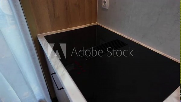 Modern electric induction cooker with built-in ventilation and extractor hood which draws steam from boiling water in a pan. Steam from a boiling pot is drawn into the integrated range hood