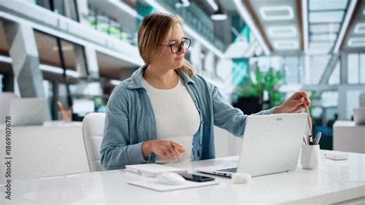 Woman Finishing Her Work Day At Office Desk And Closing Laptop Computer