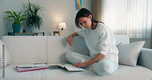 Young female student studying in campus room, female person preparing for exam sitting on couch