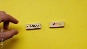 a Yellow warm background without shadows the male hand laid wooden cubes with colored words laid out the black word at school LGBT