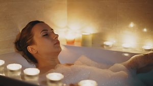 Woman enjoying a relaxing bubble bath surrounded by candles - Free Stock Video