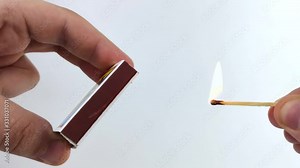 Men's hands light a match on the boxes. Macro video of a match head ignition. Concept of burning fire on a white background as a sign of the safe use of matches.