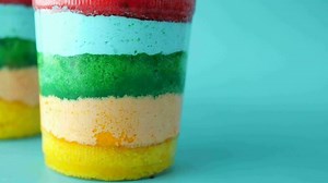 Rainbow color cake in a plastic container on table