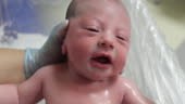 Newborn baby crying taking bath