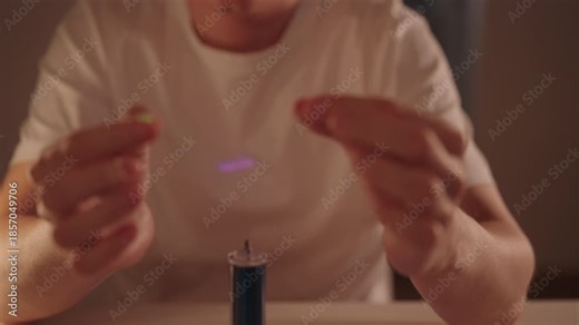 Person hands holding led bulbs illuminating near tesla coil during physics experiment, demonstrating wireless power transmission and principles of electromagnetic induction in dark lab room, close-up.