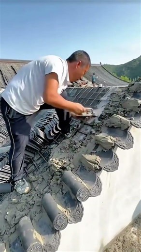 building a traditional curved roof with ornamental tiles and wet cement using a metal trowel tool