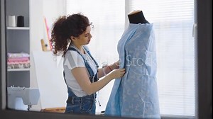The seamstress in the atelier works with a textile on the mannequin