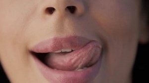 Lips kiss in natural day light. Beauty sexy female model full pink lips close-up. Woman mouth slow motion RED camera shot. Perfect soft skin sexy multi racial diverse model licking lips with tongue
