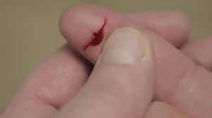 Paper cut on finger with drop of blood close up | Premium Stock Video Footage