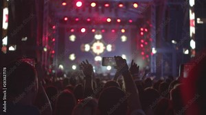 Night iconic concert. People cheer move and clap their hands in unison against the strobing stage lights.