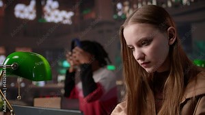 Focused student girl collecting notes for academic lessons at university library, making exam preparations and working on her diploma project. Young adult searching for citations. Camera B.