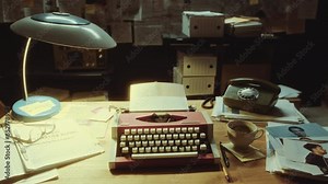 Vintage typewriter, desk lamp, landline phone, criminal investigation report, documents and mugshots on office table of detective during night