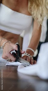 Vertical video of tailor work desk, background blurred video. Female hands using scissors cut out a sample of a new T-shirt model from white eco-friendly cotton fabric. A clothing designer.