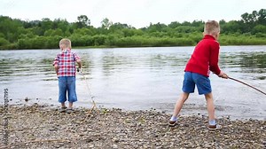 Two children play on the river Bank. Throw stones, make splashes of water. Beautiful summer landscape.