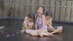 Three multiethnic siblings leap and bounce around on their backyard...