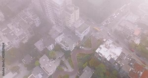 Descending through the thick fog over the beautiful city. Aerial footage over Lombard Street in San Francisco, California, USA.