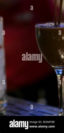 Bartender prepares a coffee-flavored alcoholic cocktail at the bar. A glass with ice sits nearby. European nightlife, drink preparation, mixology, cocktail making, bar beverage scene Stock Video Footage - Alamy