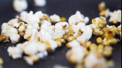 Close-up shot of popcorn popping, exploding in slow motion in a pan
