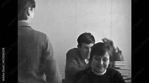 Adult students sitting at school desks, teacher conducting lesson in university classroom. School, university learning atmosphere. Vintage black white film. Education college archive. Retro 1980s