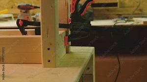 The master fastens the wood parts with a screwdriver fastened with a clamp