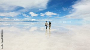Man and woman walking away on the lake Salar de Uyuni, Bolivia