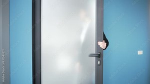 Female office worker in black suit opening a glass door. Professional woman entering office space. Person depicted in modern corporate setting, making entrance. Concept of entering new opportunities