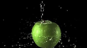 Super slow motion water droplets fall on the rotating apple. On a black background. Filmed on a high-speed camera at 1000 fps.