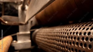 Obsolete paper press machine with perforated drum and rollers in workshop closeup. Old machine for papermaking in technology museum