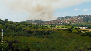 Dangerous forest fire without control of fire brigade gets close to residential homes on a village or town on a hill. Climate change disastrous effects on nature in spain, draught cause forest fire