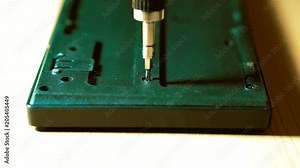 Closeup of a hand which unscrew the screw. In the hands of a screwdriver with interchangeable nozzles. keyboard