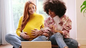 4k video of a couple of women showing the ultrasound online in a video call. Concept: motherhood, pride, connection