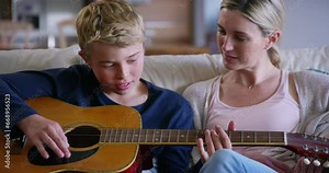 Mother, son and happy with guitar on sofa with teaching, learning and instructions in living room of home. Family, woman and kid with instrument, communication and support on couch in lounge of house