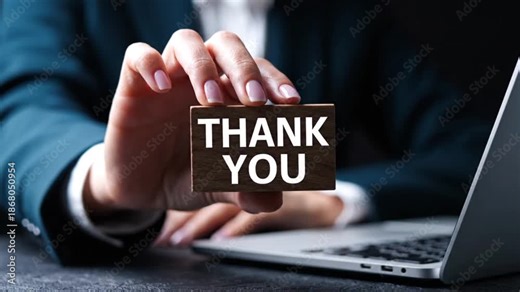 A businesswoman extends a hand presenting a wooden card inscribed with thank you near a laptop computer signifying gratitude and appreciation