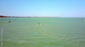 windsurfer beginner stands on board and sails