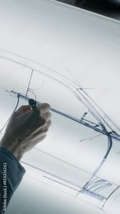 Senior automotive male designer drawing sketch blueprint with marker at the light table, developing futuristic electric car future design. He working in modern car design development studio. Vertical