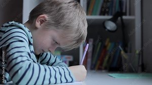 Happy little kid boy at home making homework at the morning