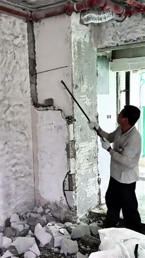 A person is demolishing concrete wall using crowbar