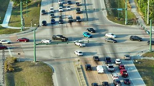 View from above of wide multilane road with driving vehicles at intersection with traffic lights. City transportation in the USA. American urban traffic