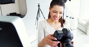 Photographer looking at photos on digital camera in studio 4k