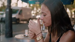 Young French woman smokes a cigarette while sitting in a street cafe in Paris