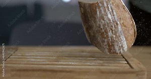 Falling traditional rustic bread in slow-motion captured with high-speed camera with flour and crumbs flying in the air
